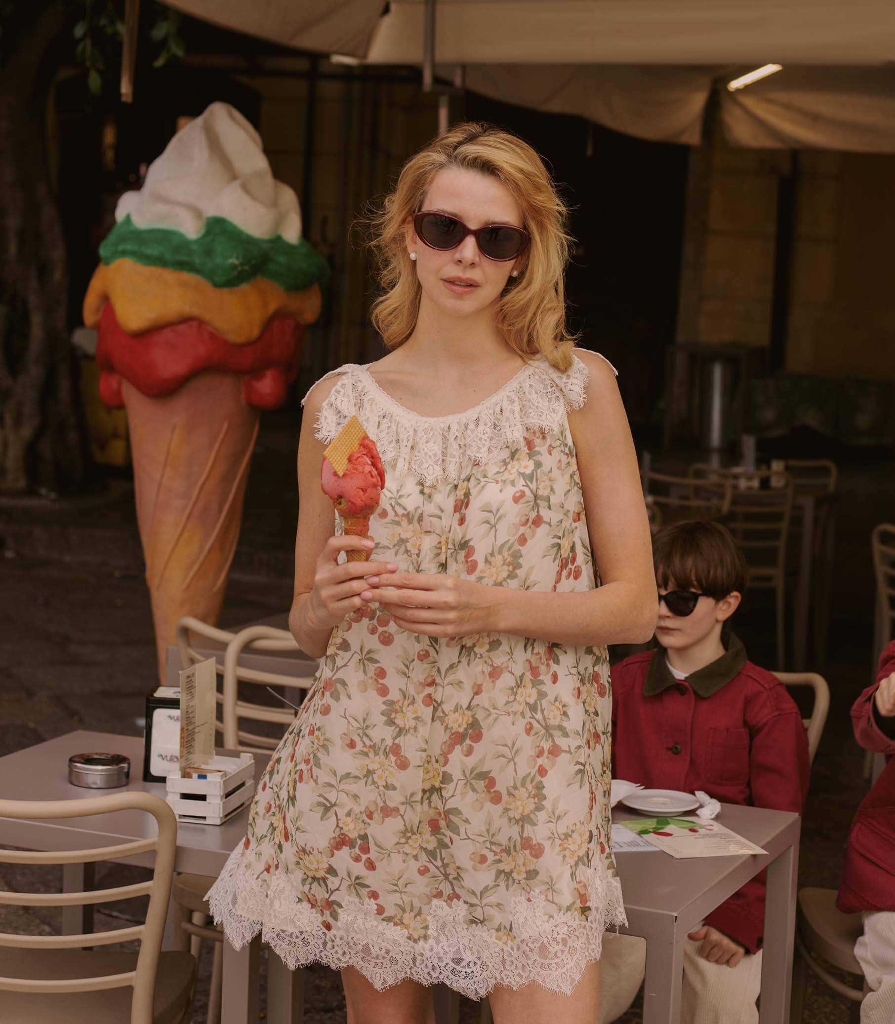 Woman enjoying ice cream in a floral dress from the Dresses collection, summer vibe, casual outdoor setting.